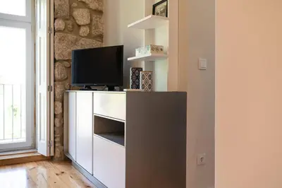 a living room with a television on a white cabinet at Casa Nina in Porto