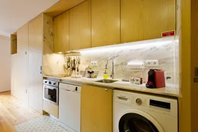 a kitchen with a washing machine and a sink at Miragaia Rio in Porto