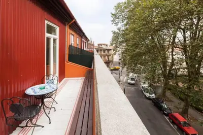 a balcony with a table on a red building at GuestReady - Beige Glamour in Porto