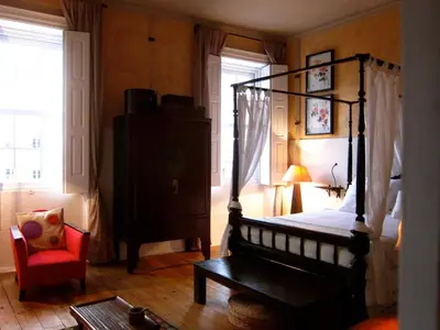 a bedroom with a canopy bed and a red chair at VIVA Fabulous Old World in Porto