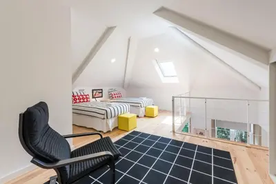 a attic room with a chair and a bed at GuestReady - Belas Artes Duplex in Porto
