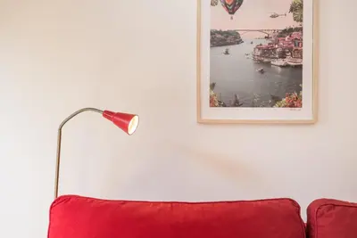 a red couch with a lamp and a picture on the wall at GuestReady - Belas Artes Duplex in Porto