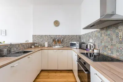 a kitchen with white cabinets and a tile wall at GuestReady - Cityscape coastal flat in Porto