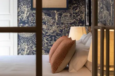 a bed with a pillow on it with blue wallpaper at Líbere Porto Laranjais in Porto