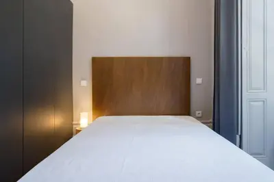 a bedroom with a white bed with a wooden headboard at Oporto Sao Lazaro Apartment in Porto