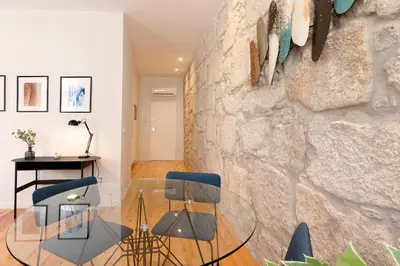 a dining room with a glass table against a stone wall at HM – Oporto Downtown Swimming Pool Apartment in Porto