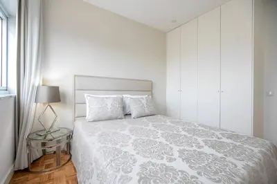 a white bedroom with a bed and a side table at Casa D'Ouro Apartment by Oporto Soul in Porto