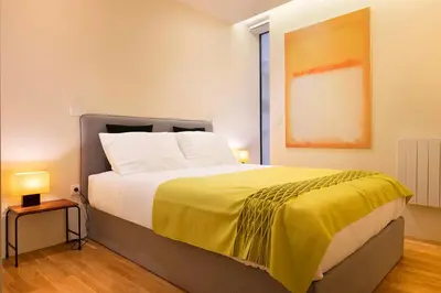 a bedroom with a large bed with a yellow blanket at Ribeira Trendy Flat in Medieval Mercadores Street in Porto
