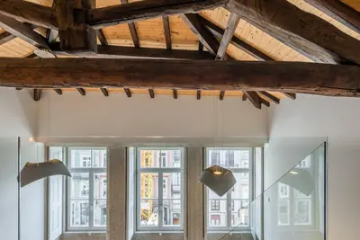 a room with windows and wooden ceilings and lights at GuestReady - RiverWood Mezz in Porto