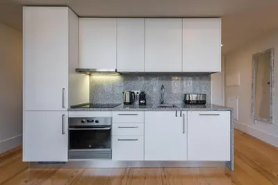 a kitchen with white cabinets and a stove at GuestReady - RiverWood Mezz in Porto
