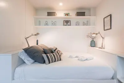 a white bedroom with a bed with two lamps at GuestReady - Lazaro Studio in Porto