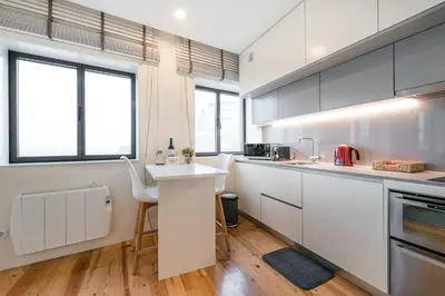 a kitchen with white cabinets and a counter with a table at GuestReady - Lazaro Studio in Porto