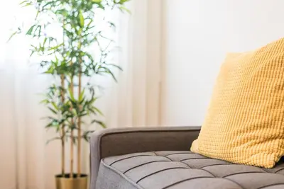 a couch with a yellow pillow and two plants at GuestReady - Square Painted Ceuta in Porto