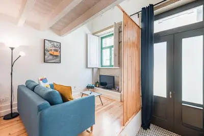 a living room with a blue couch and a tv at GuestReady - Ladder Mezz in Porto