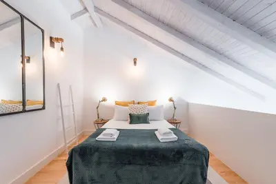 a bedroom with a large bed in a white room at GuestReady - Ladder Mezz in Porto