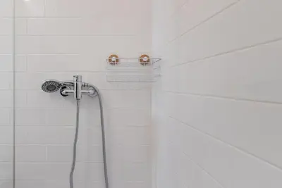 a shower with a hose in a white tiled bathroom at GuestReady - Ladder Mezz in Porto