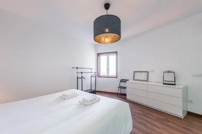 a white bedroom with a large white bed and a desk at GuestReady - Redamancy Flat in Porto