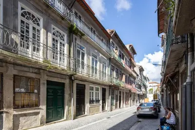 a woman walking down a street with a car at CASA JOY Cathedral apartment in Porto