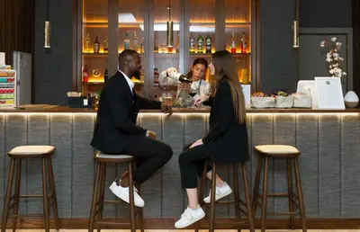 a man and woman sitting on stools at a bar at Oca Oriental Porto Hotel in Porto