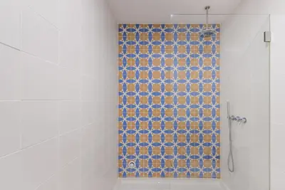 a bathroom with a shower with a blue tile wall at GuestReady - Mezuzah Yellow in Porto