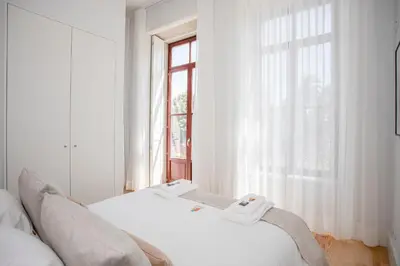 a white bedroom with a bed and a window at Liiiving in Porto - City View Apartments in Porto
