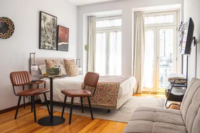 a bedroom with a bed and a table and chairs at Impar Studios Deluxe in Porto