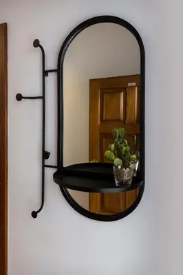 a black mirror hanging on a wall with a plant at Impar Studios Deluxe in Porto