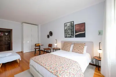 a white bedroom with a bed and a table and chairs at Impar Studios Deluxe in Porto