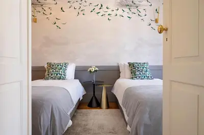 two beds in a room with birds on the wall at Historic apartment at Cardosas with balcony in Porto