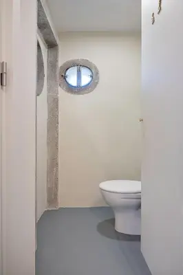 a bathroom with a white toilet and a window at Historic apartment at Cardosas with balcony in Porto