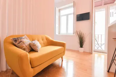 a living room with a yellow chair and a television at Sweet Home Firmeza in Porto