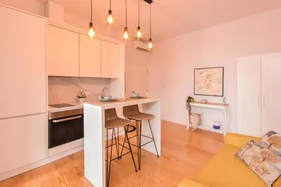 a kitchen and living room with a counter and stools at Sweet Home Firmeza in Porto
