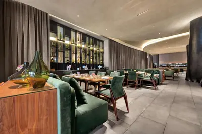 a dining room with tables and green chairs at Hilton Porto Gaia in Vila Nova de Gaia
