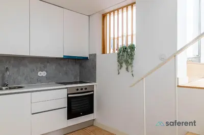 a kitchen with white cabinets and a sink at Stylish Triplex next to Ribeira in Porto