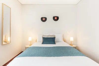 a bedroom with a white bed and two lamps at D&S - Family Apartments II in Porto