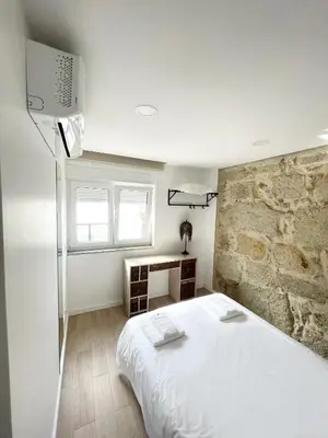 a bedroom with a white bed and a stone wall at Portoo Blue Apartments - Douro in Vila Nova de Gaia