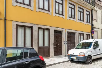 two cars parked in front of a yellow building at Douro Golden Studio in Porto
