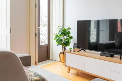 a living room with a flat screen tv on a cabinet at Douro Golden Studio in Porto