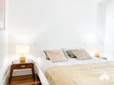 a white bedroom with a bed and two lamps at The Wondrous Central Apartment in Porto