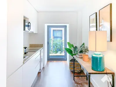 a kitchen with white cabinets and a table with a plant at The Wondrous Central Apartment in Porto