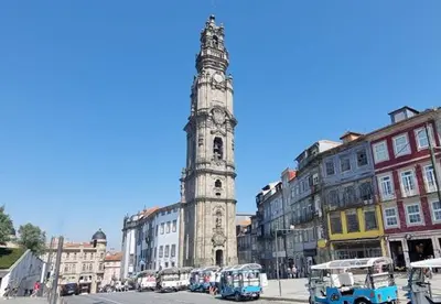 a tall clock tower in a city with buses at The Beautiful Ones Studio in Porto