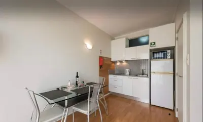 a kitchen with white cabinets and a table and chairs at Silver Duque in Porto