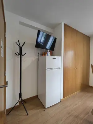 a room with a white refrigerator and a tv on the wall at Get Cozy in Porto