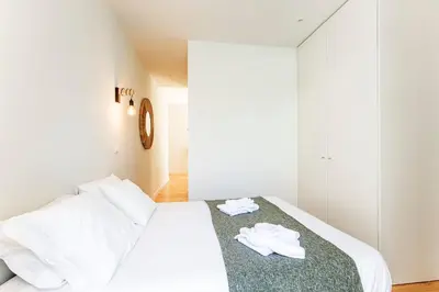a bedroom with a white bed with two white towels on it at Central Studio with Pool & Patio by LovelyStay in Porto
