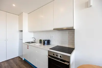 a kitchen with white cabinets and a stove top oven at Elegant Studio w/ AC & Balcony by LovelyStay in Porto
