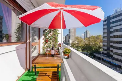a table with a red and white umbrella on a balcony at Sunny Oporto, Trindade Balcony in Porto