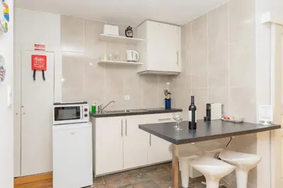 a kitchen with white cabinets and a table with stools at Sunny Oporto, Douro Apartments in Porto