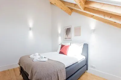 a small bedroom with a bed with a blanket at Bright 3BR Flat w/ AC in City Center by LovelyStay in Porto