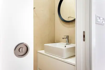 a bathroom with a sink and a mirror on the wall at Bright 3BR Flat w/ AC in City Center by LovelyStay in Porto