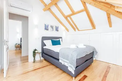 a bedroom with a bed in a room with wooden ceilings at Bright 3BR Flat w/ AC in City Center by LovelyStay in Porto